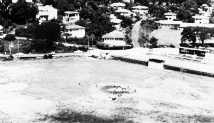 Grenadians gathered around the burnt remains of a US Marine Corps AH-1T SeaCobra in a sports field in Grenada, 25 October 1983