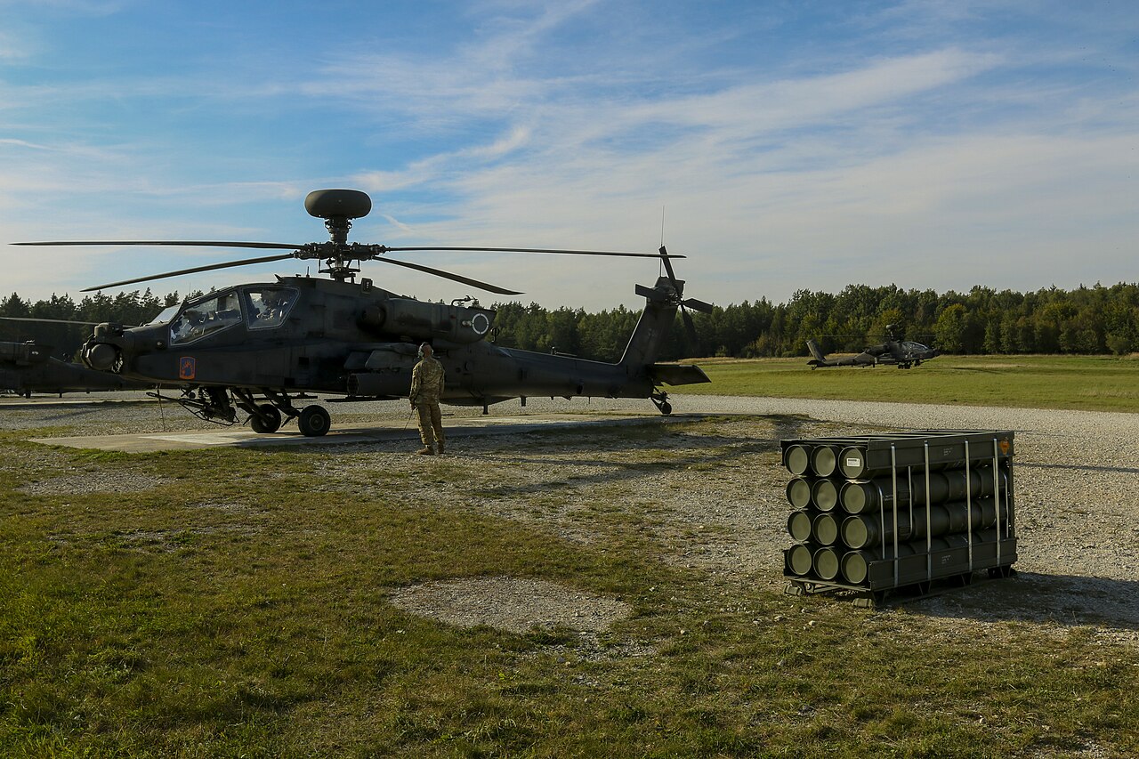 US Army AH-64D Apache helicopter on a range in Germany with containers of APKWS rockets waiting to be loaded