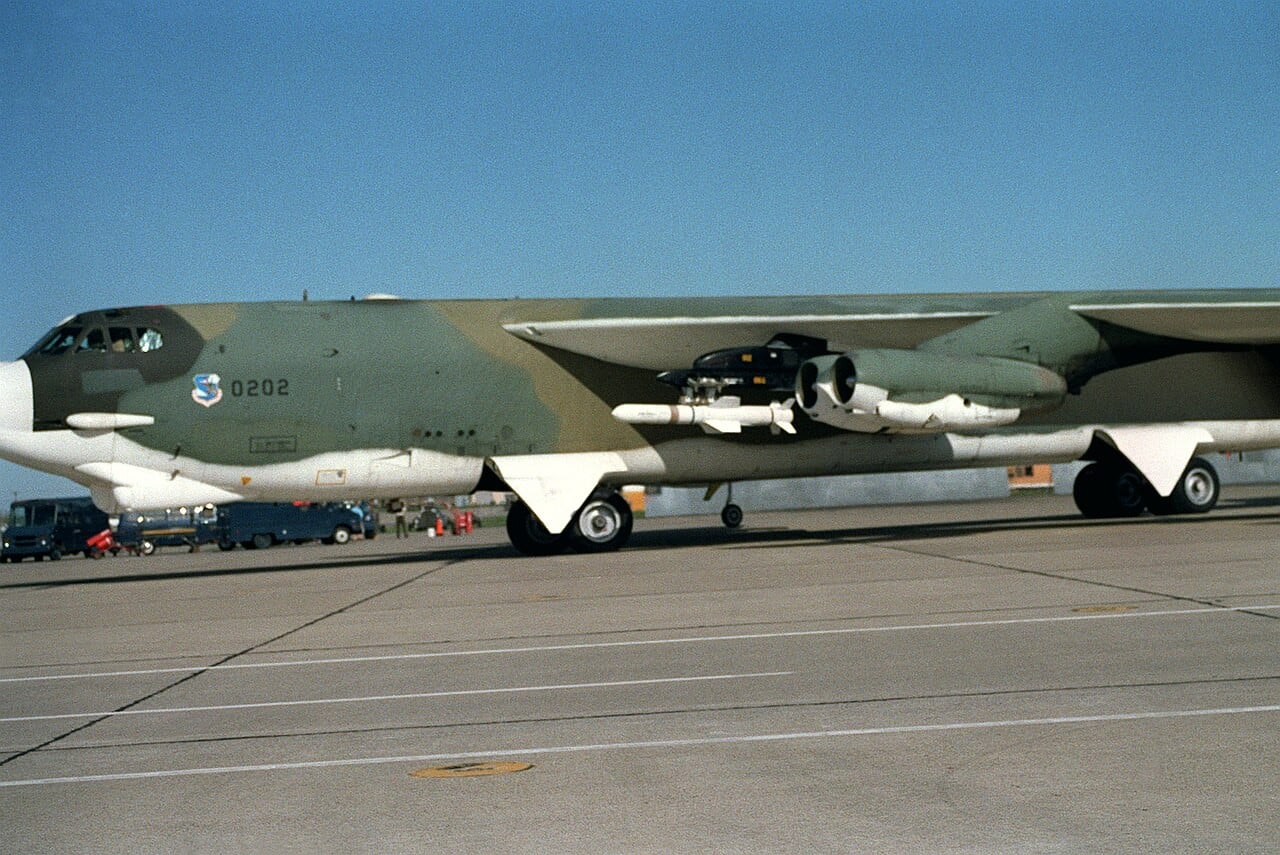 A camouflaged B-52 with an AGM-84A Harpoon anti-ship missile on its wing pylon at Mather Air Force Base, 1983