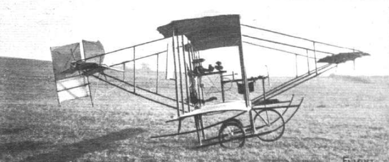 Side view of the Bland Mayfly pusher biplane standing on a grass field with its two main wheels and long skids