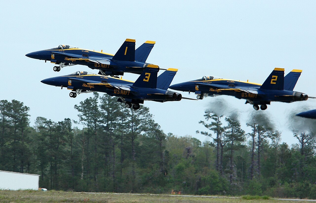 Three Blue Angels F/A-18A Hornets lifting off together in a tight formation takeoff