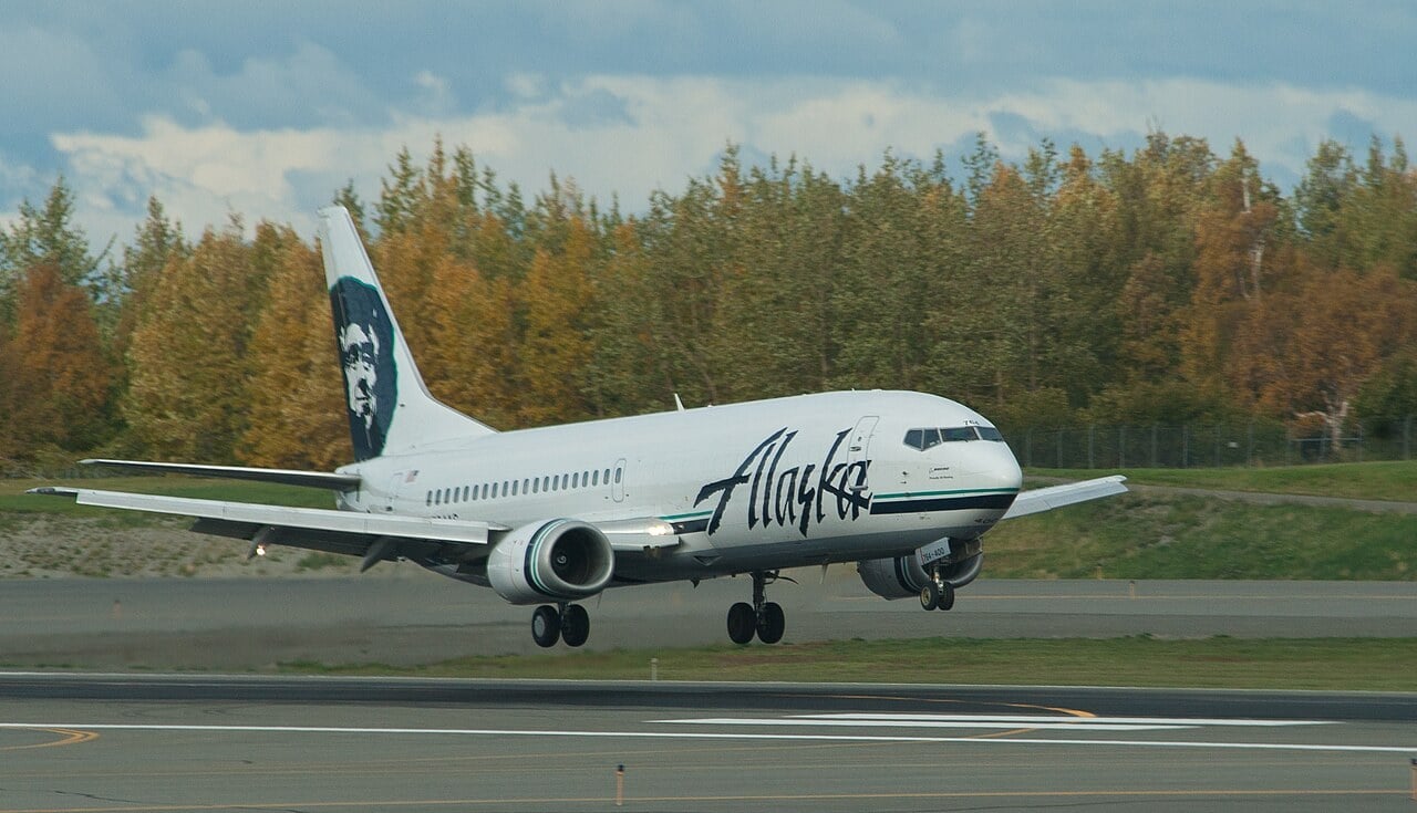 An Alaska Airlines Boeing 737 landing at Anchorage, its low-mounted wings angled upward in a shallow V