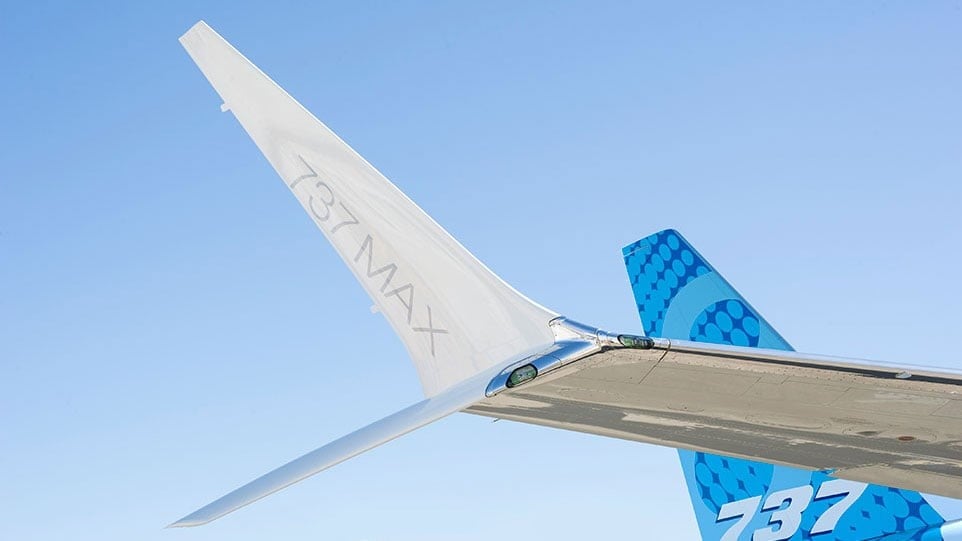 The split-tip winglet of a Boeing 737 MAX with 737 MAX lettering against a blue sky