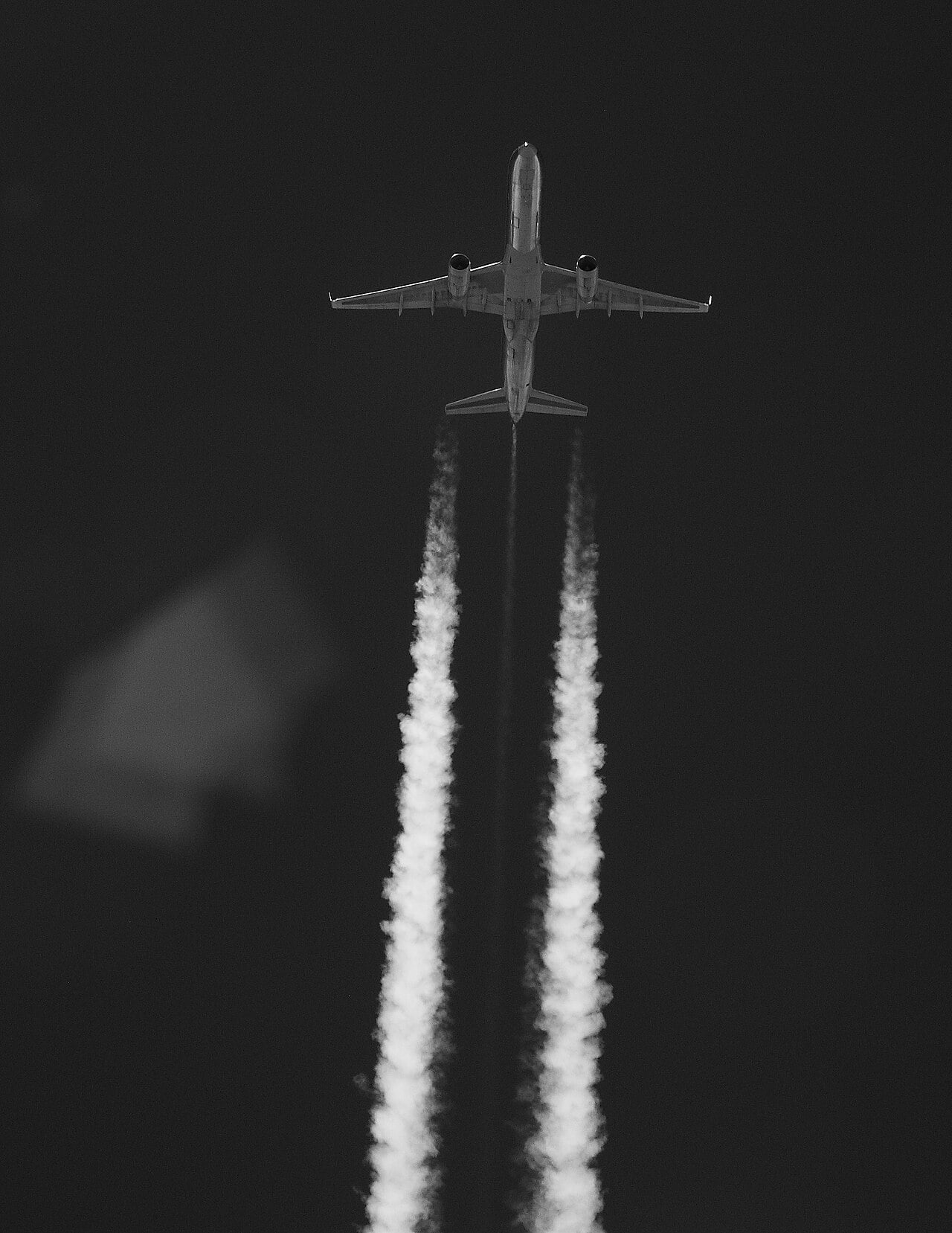 A Boeing 757 with twin contrails photographed from an aircraft 1,000 feet below