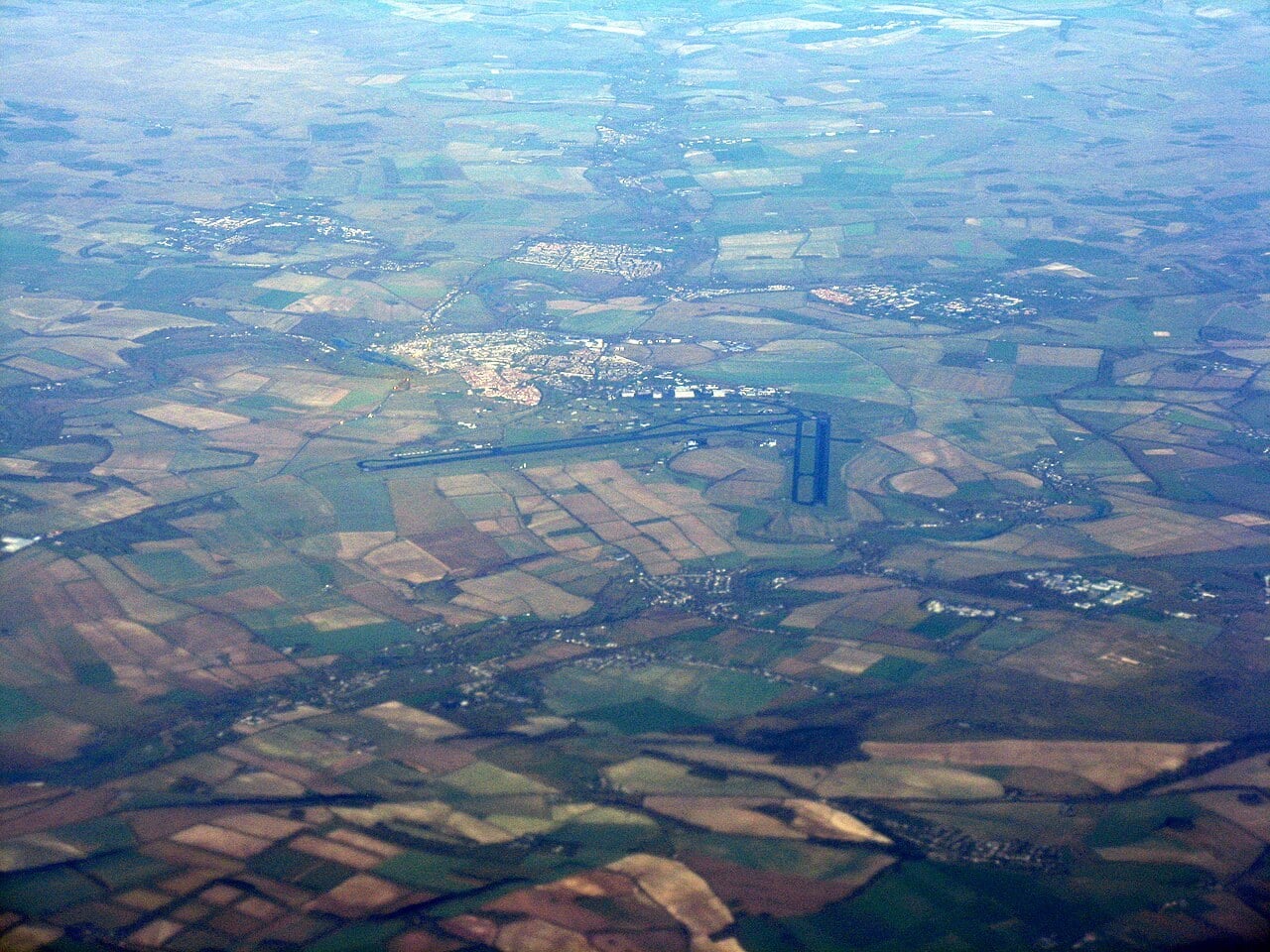 Aerial view of the MOD Boscombe Down airfield runway with the town of Amesbury in Wiltshire beyond