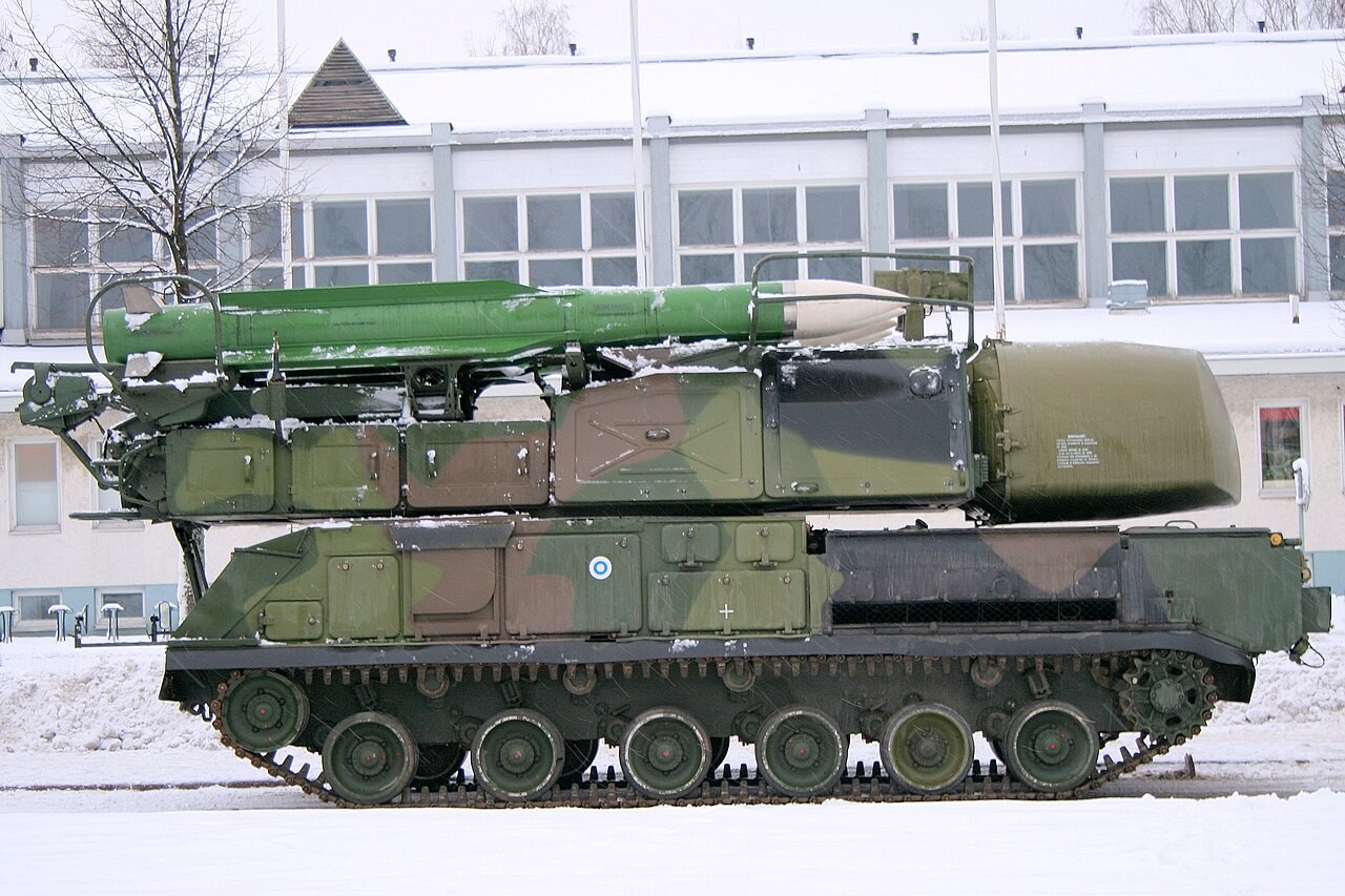 A Buk-M1 tracked missile launcher with a large green 9M38-series missile on its launch rail