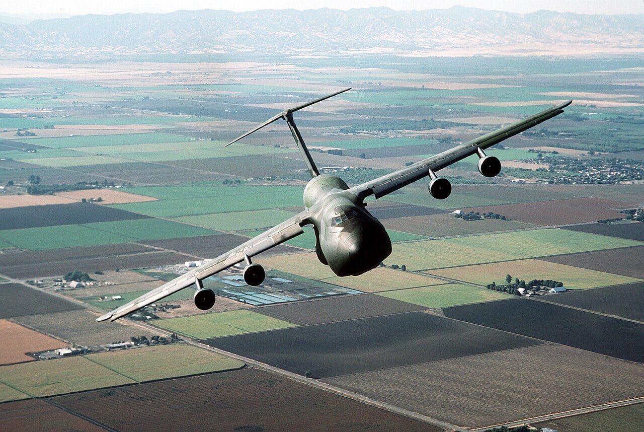 Air-to-air front view of a US Air Force C-5B Galaxy, its high-mounted swept wings drooping downward from the fuselage