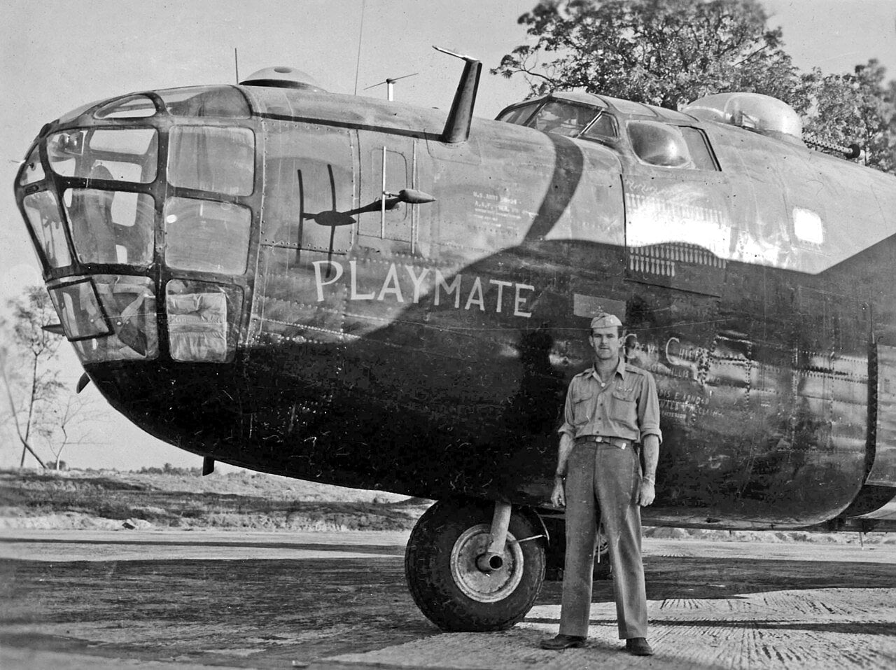 Flight engineer Sgt William T. Alexander standing beside the nose of black B-24D Liberator Playmate of the 858th Bomb Squadron, with a Rebecca radar antenna on the nose