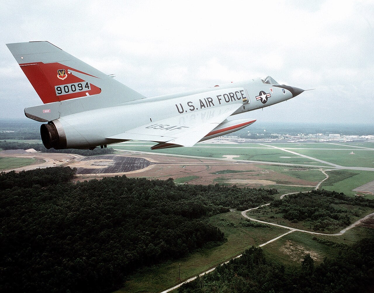 Convair F-106 Delta Dart of the 87th Fighter Interceptor Squadron in flight Convair F-106 Delta Dart of the 87th Fighter Interceptor Squadron with a red tail flying over wooded countryside