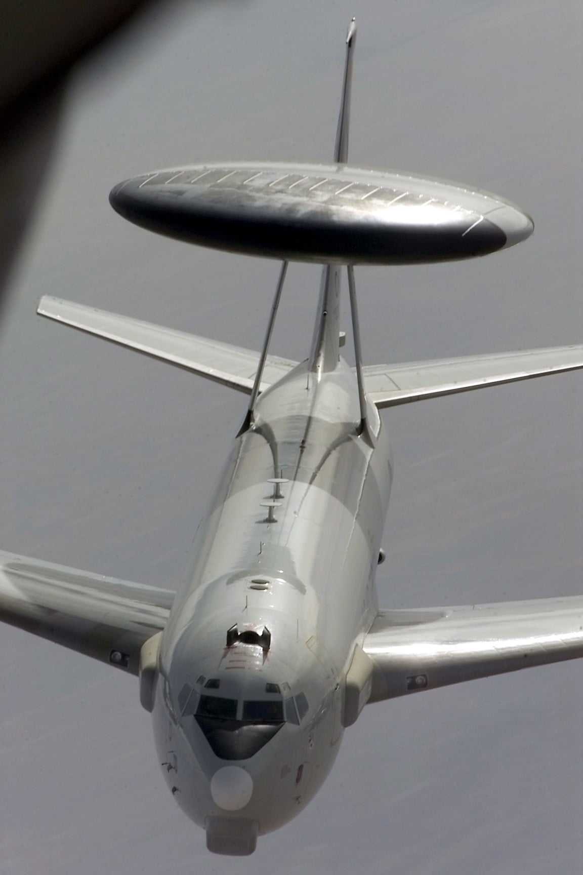A US Air Force E-3 Sentry AWACS with its rotating radar dome approaching a tanker for refuelling