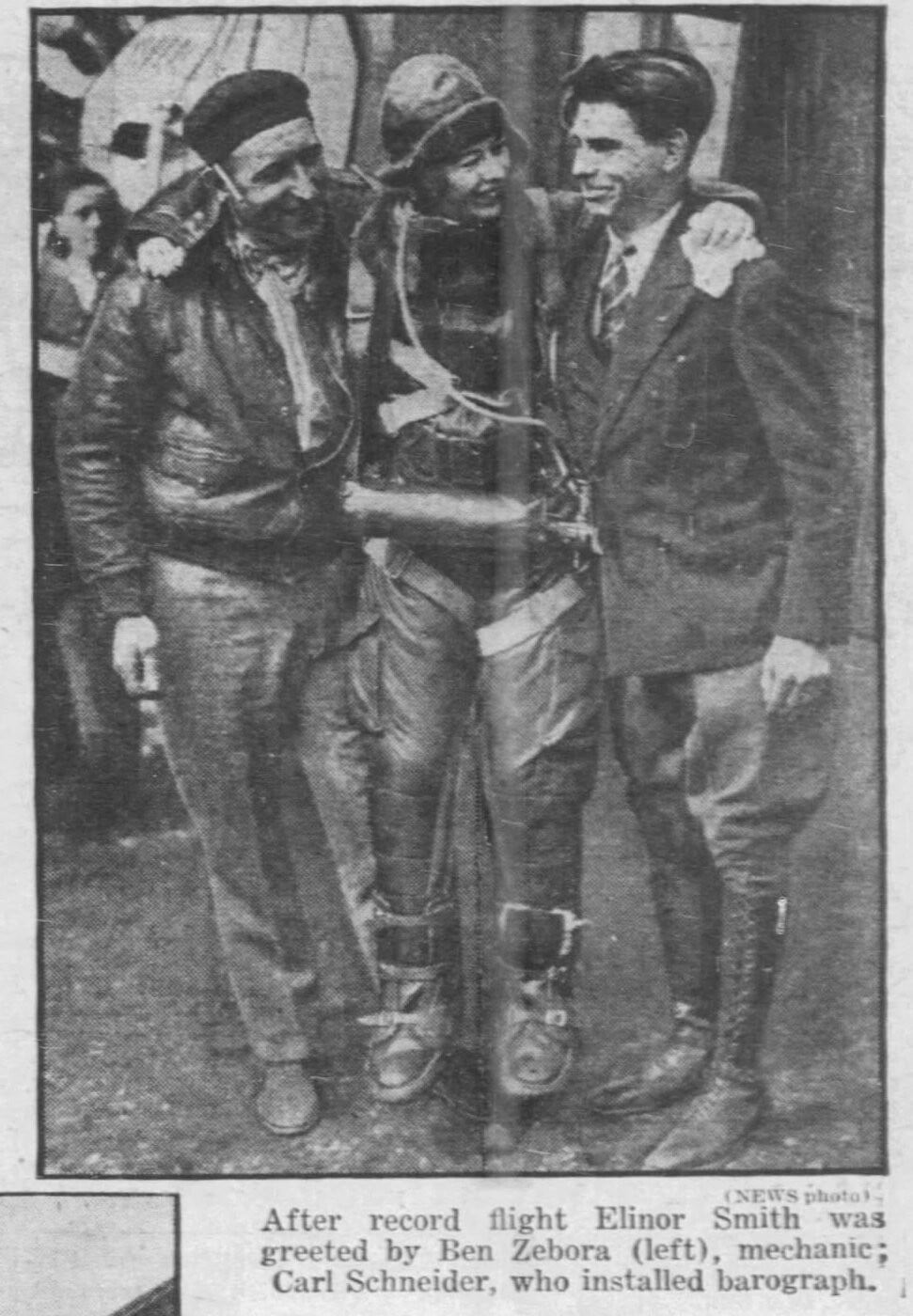 Newspaper photo of Elinor Smith in a heavy flying suit flanked by her mechanic and the man who installed the barograph after her altitude record flight