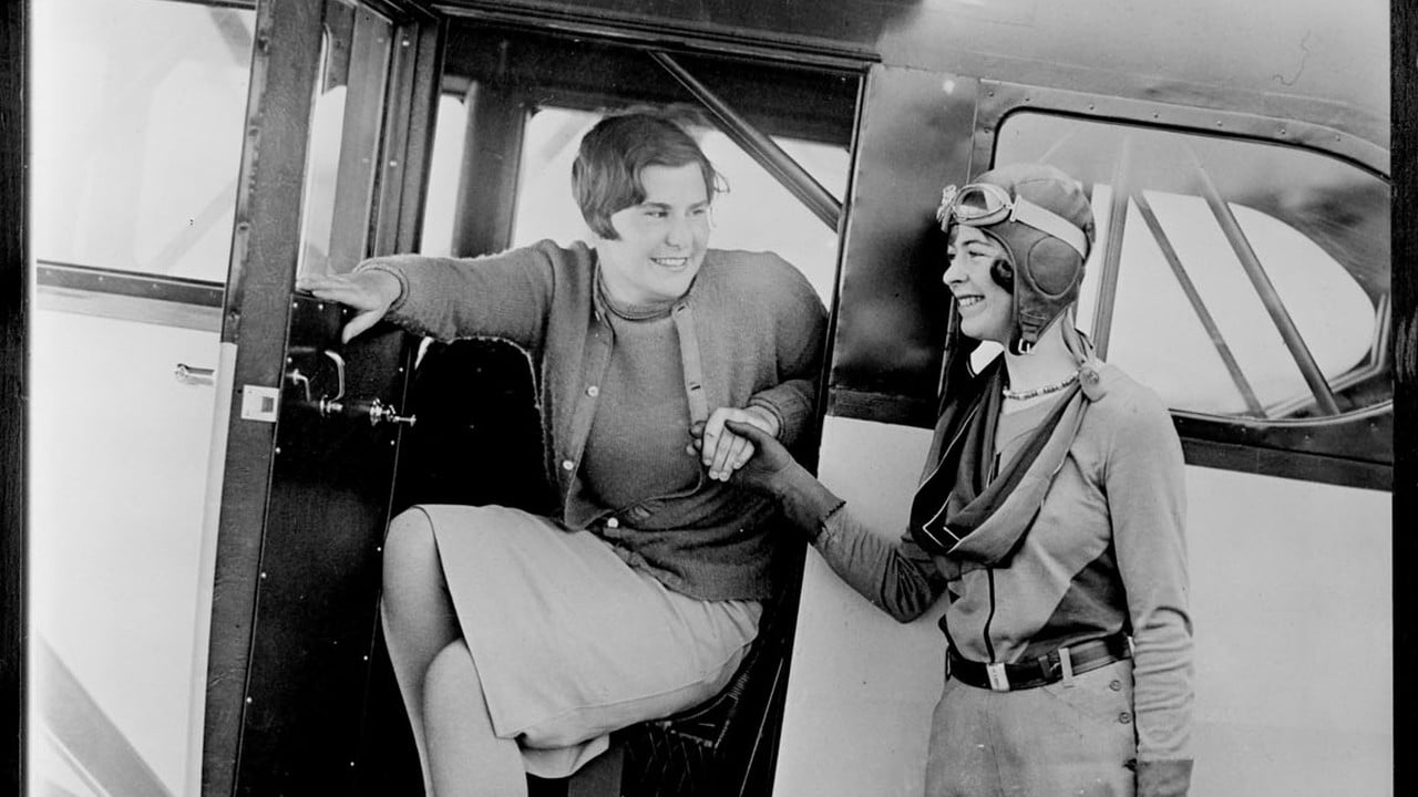 Elinor Smith at Fairchild Field, Farmingdale Teenage aviator Elinor Smith in flying helmet and goggles, right, with golfer Helen Hicks seated in an aircraft doorway at Fairchild Field, Farmingdale, New York