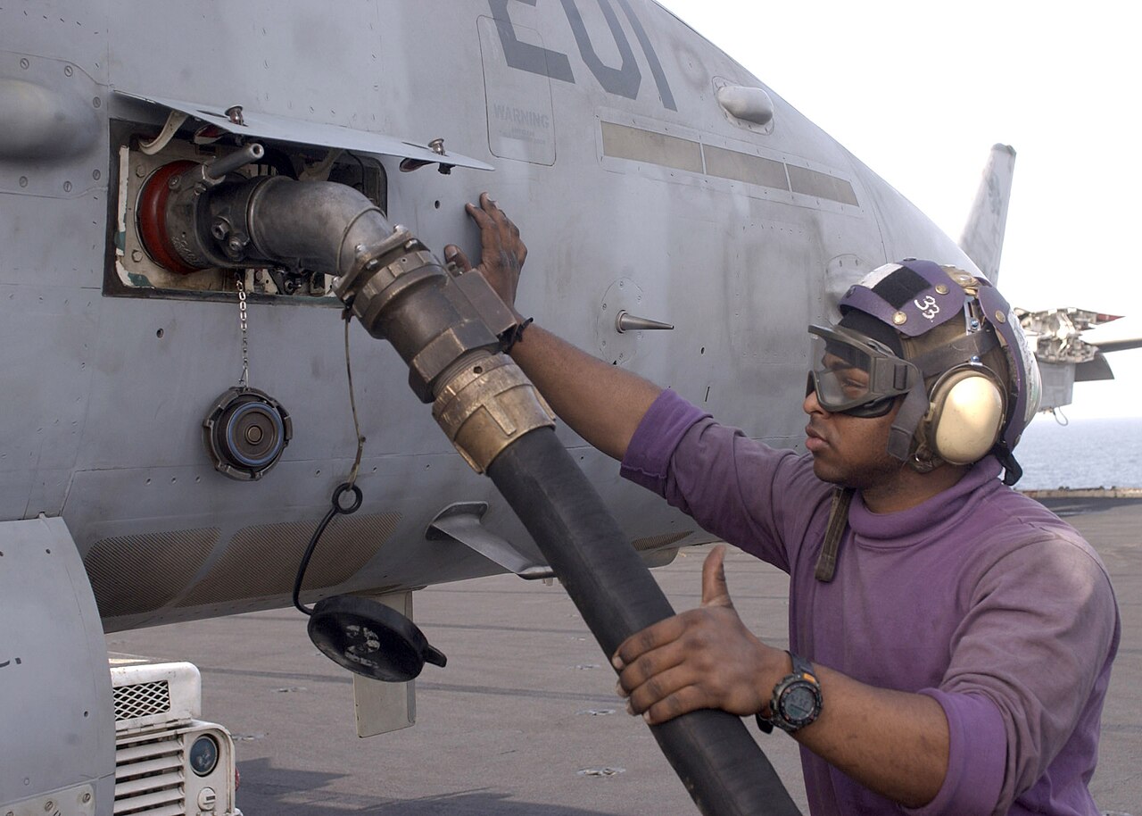 A US Navy sailor refuelling an F/A-18 Hornet on the flight deck of USS Constellation