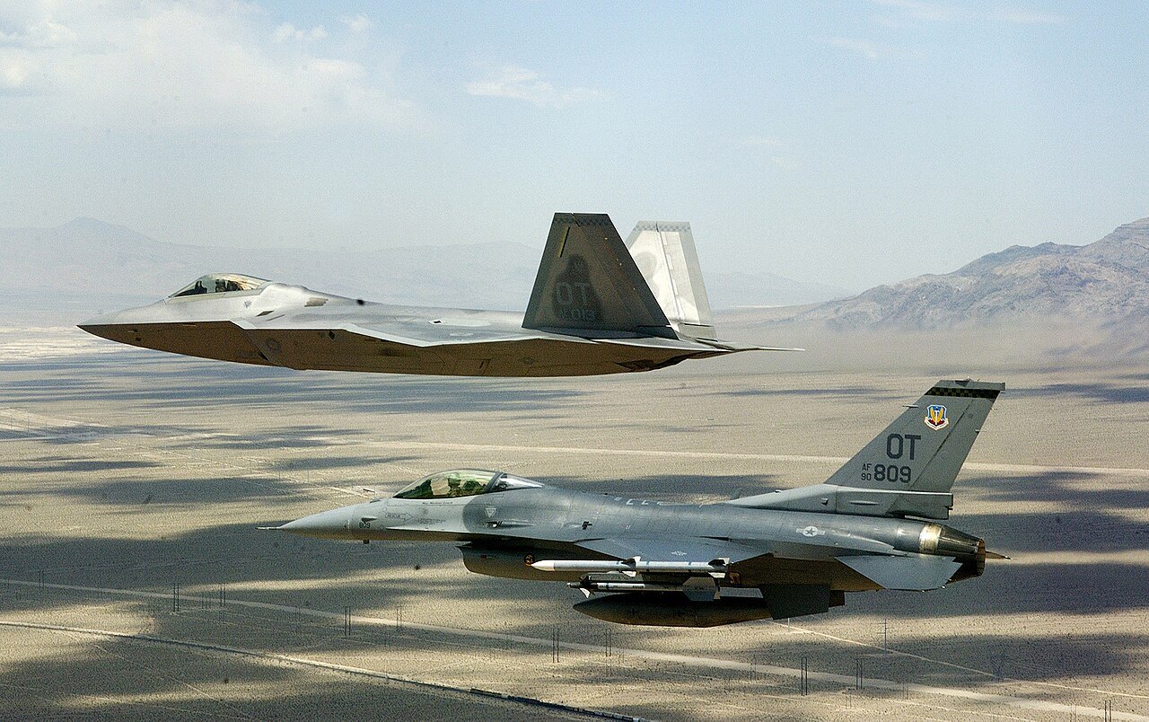 A US Air Force F-22 Raptor and an F-16 Fighting Falcon flying in formation over the Nevada desert