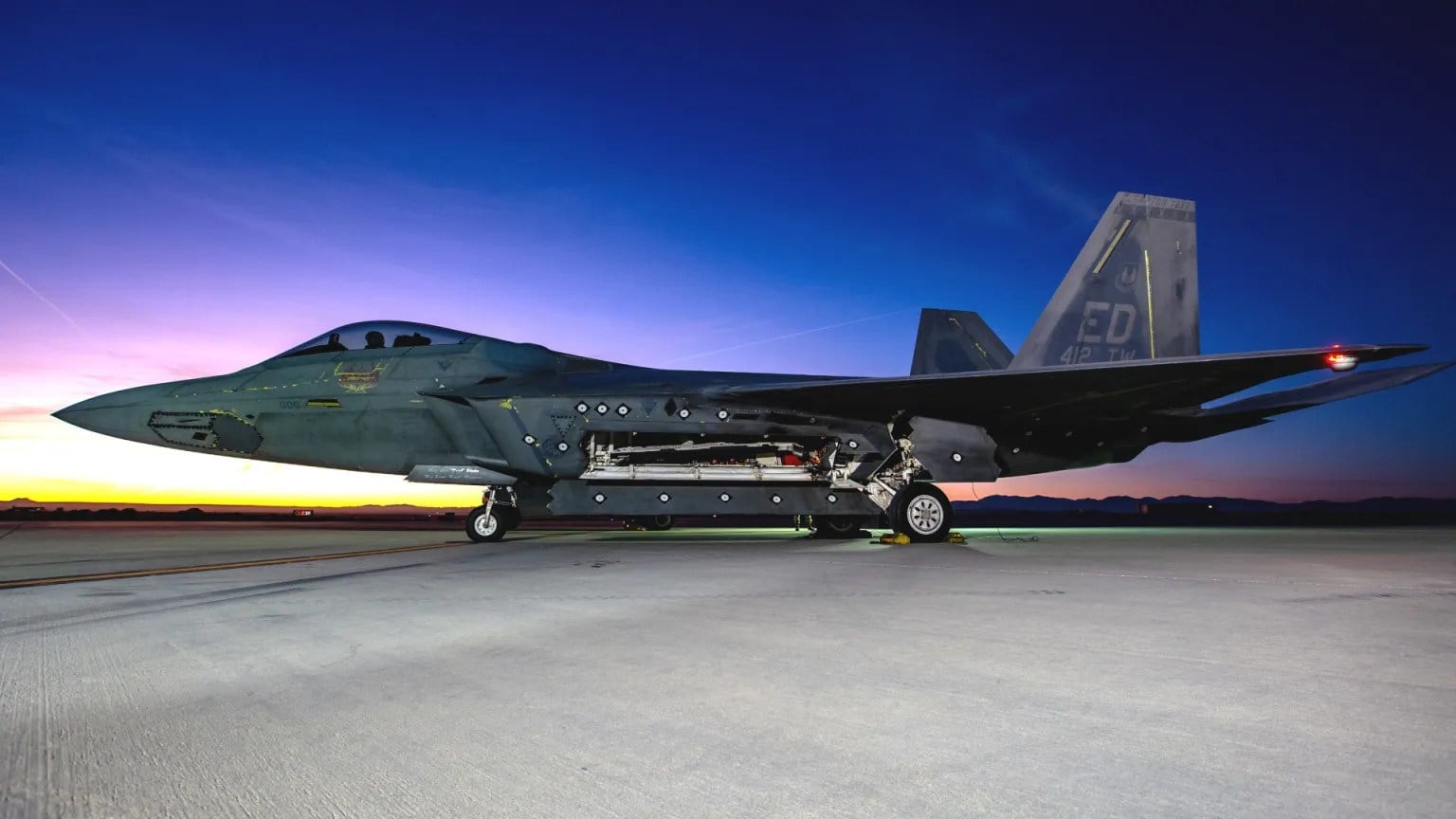 F-22 Raptor test jet of the 412th Test Wing at Edwards Air Force Base at dusk with its main weapons bay open