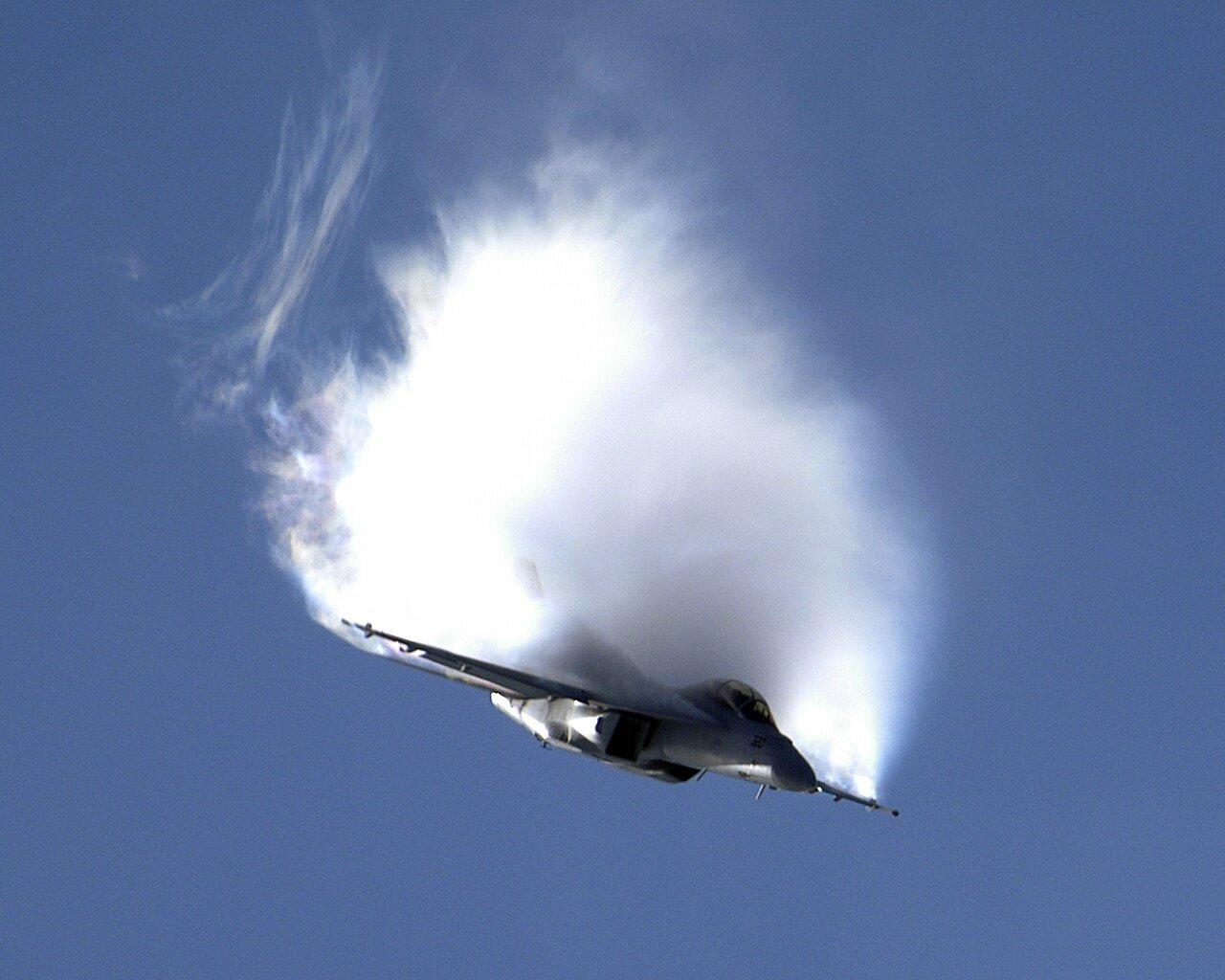 F/A-18F Super Hornet in a hard pull with a large white condensation cloud above its wings