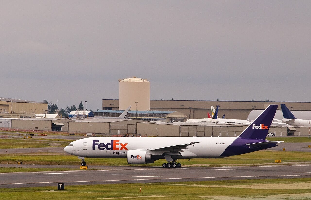 FedEx Express Boeing 777F N890FD taxiing at Paine Field with Boeing Everett factory buildings behind