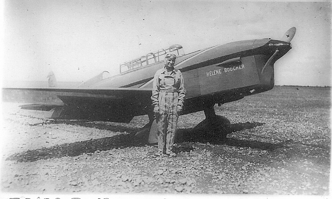 Hélène Boucher in overalls standing in front of a Caudron Rafale with her name painted on the cowling