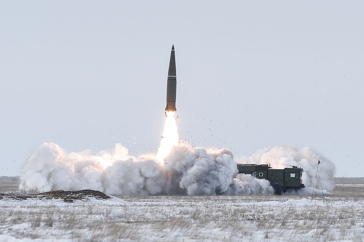 Russian Iskander-M ballistic missile climbing away from its launcher in a cloud of smoke over a snowy test range
