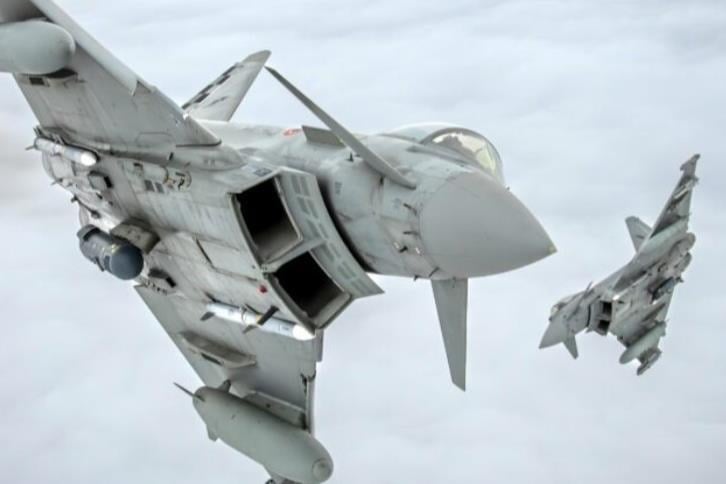 Two Italian Air Force Eurofighter Typhoons armed with missiles flying above the clouds