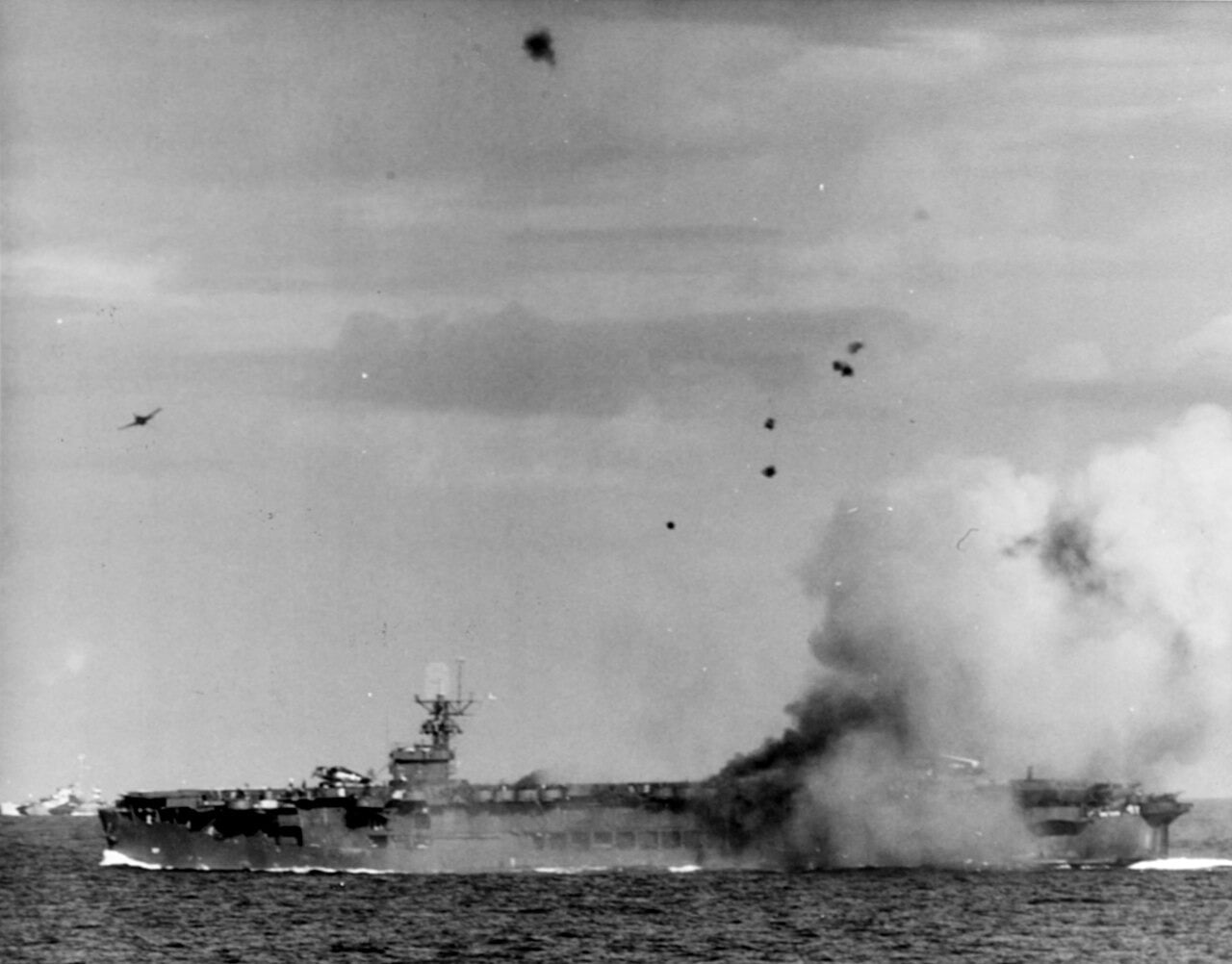 A Japanese kamikaze Zero explodes on the escort carrier USS Suwannee as a Hellcat pulls away, 25 October 1944