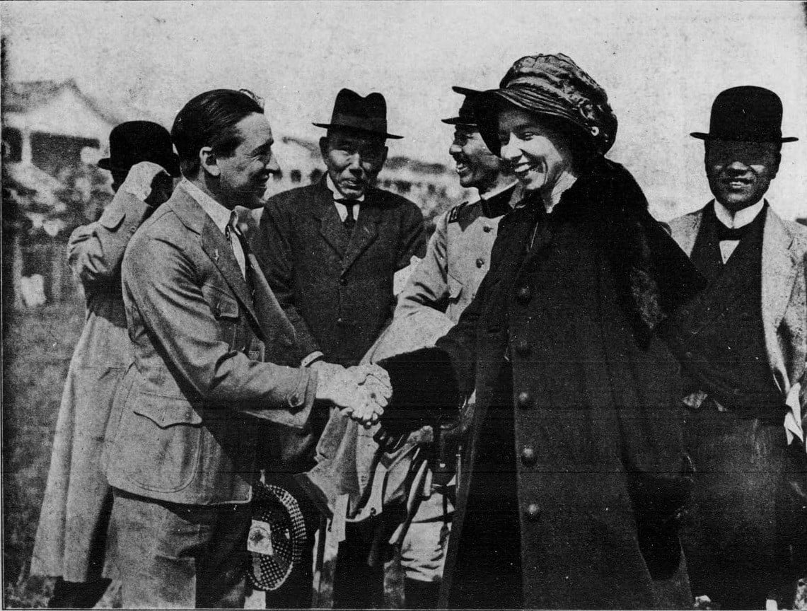 Katherine Stinson in a fur-collared coat shaking hands with American aviator Art Smith in Osaka, Japan