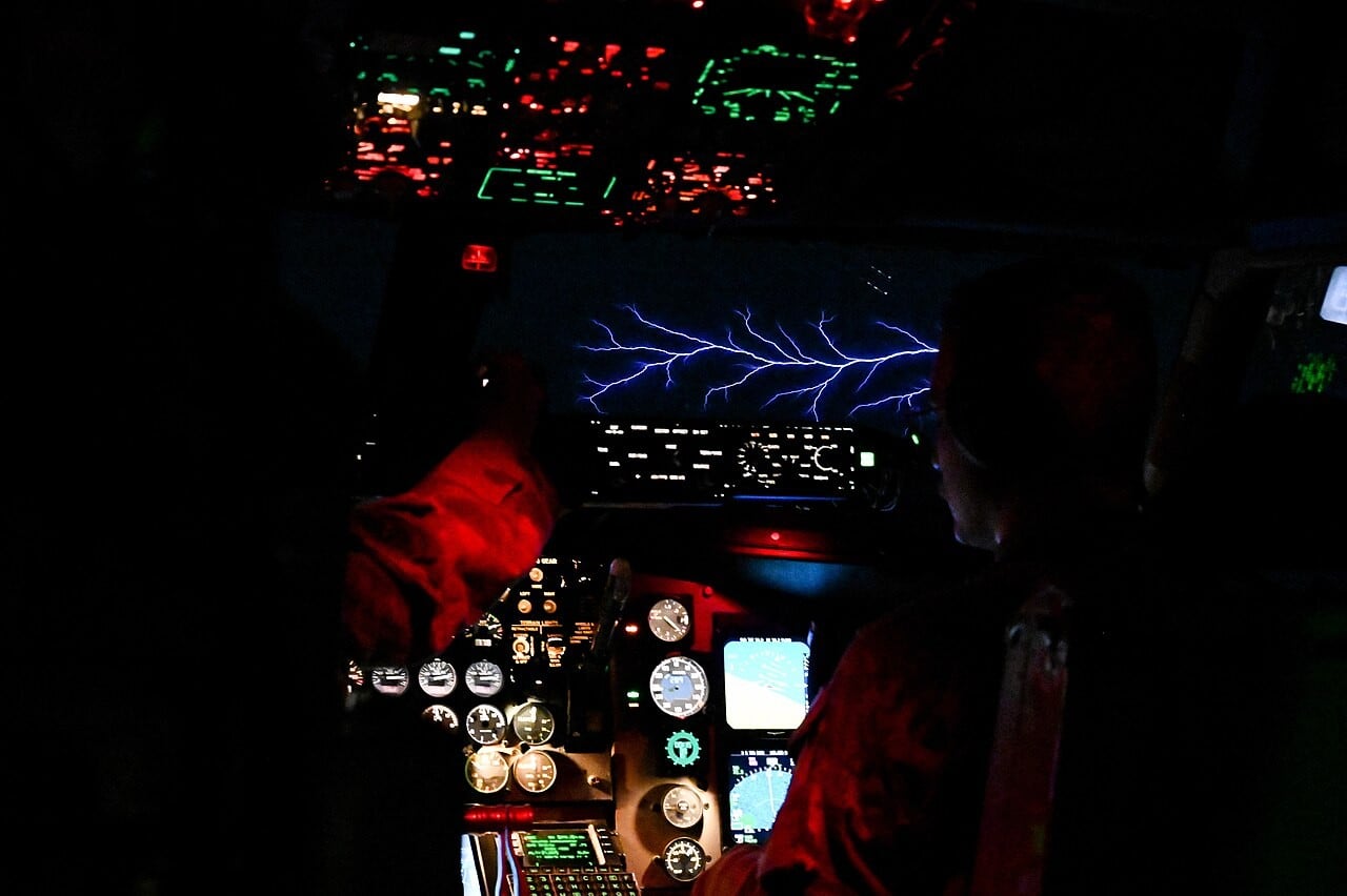 Two KC-135 Stratotanker pilots in a dark cockpit with a band of St Elmo&rsquo;s fire glowing across the windscreen