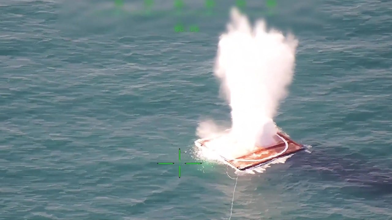 A KGK-84 guided bomb striking a floating target raft at sea, seen from an aerial camera