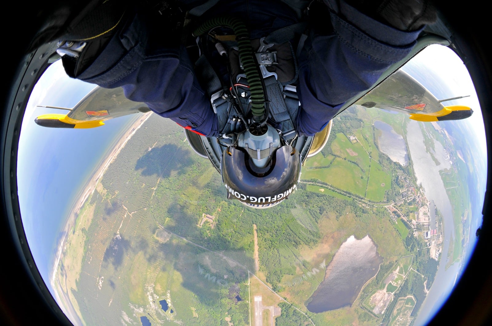 View from the rear cockpit of an Aero L-39 Albatros during a passenger flight, the aircraft banking over coastline and farmland