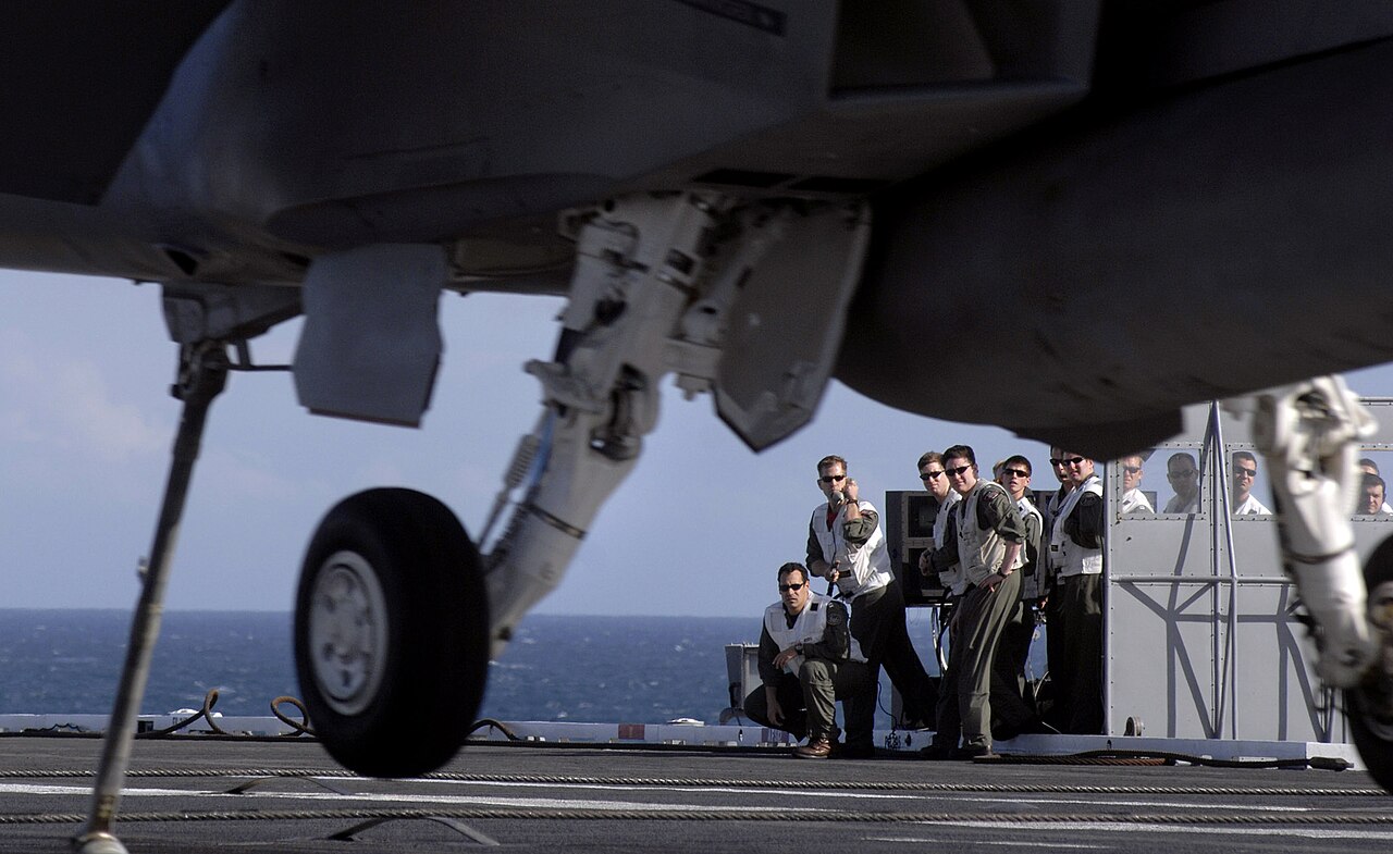Landing signal officers on the platform of USS Harry S. Truman as a Super Hornet lands