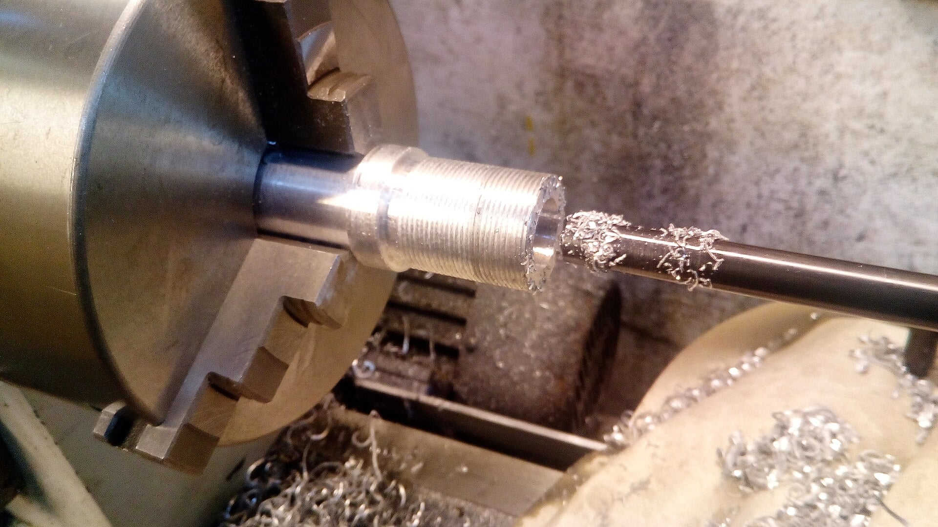 A boring bar cutting a threaded metal component on a lathe