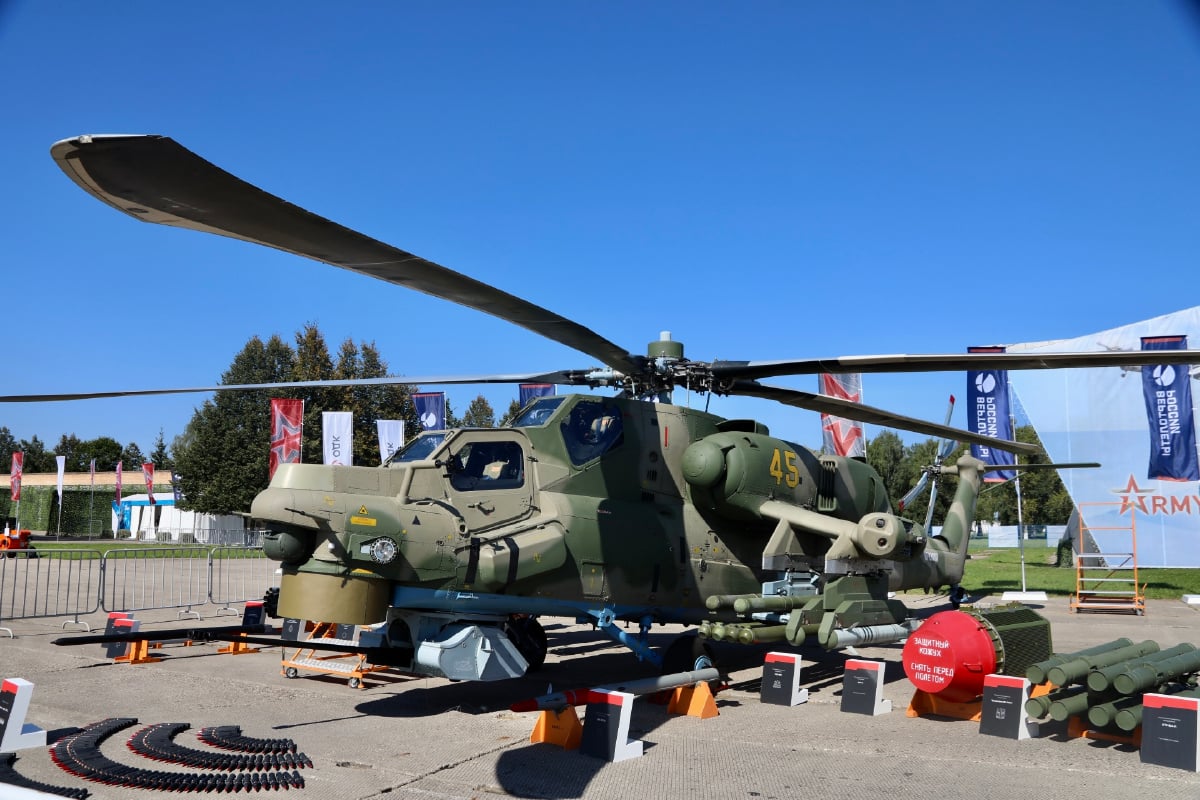 Russian Mi-28NM attack helicopter on static display with its 30 mm chin cannon, rocket pods and guided missiles laid out in front