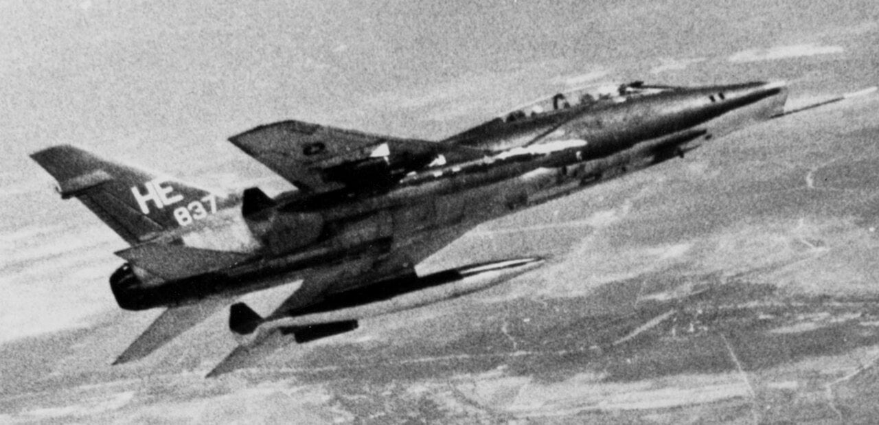 Black-and-white photo of F-100F Super Sabre 56-3837, tail code HE, in flight over Southeast Asia in July 1968