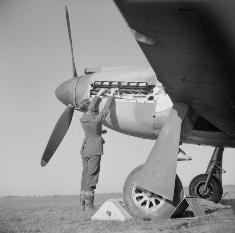 A mechanic works on the exposed Allison V-12 engine of an RAF North American Mustang Mk I on an airfield in Buckinghamshire