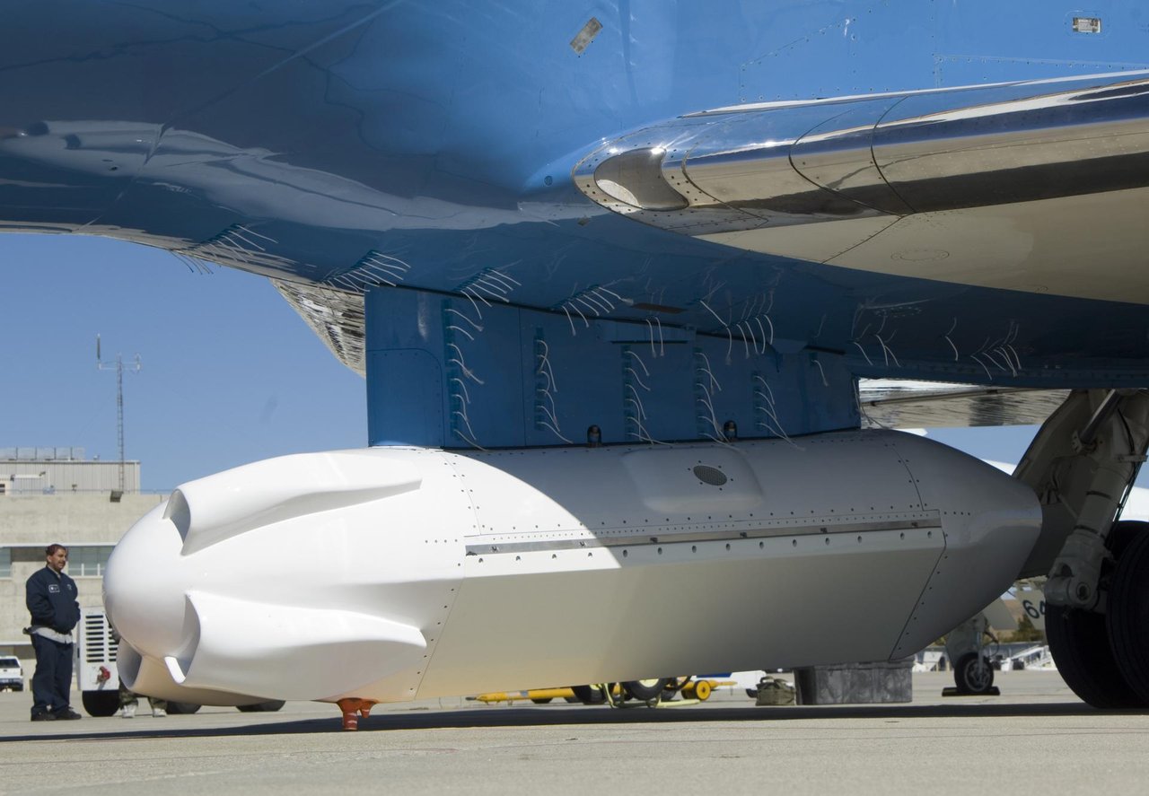 Rows of white tufts fixed to the pylon and belly of a NASA Gulfstream III above a white sensor pod
