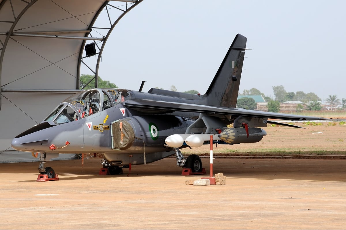 A Nigerian Air Force Alpha Jet in grey camouflage parked in front of a shelter at Kaduna