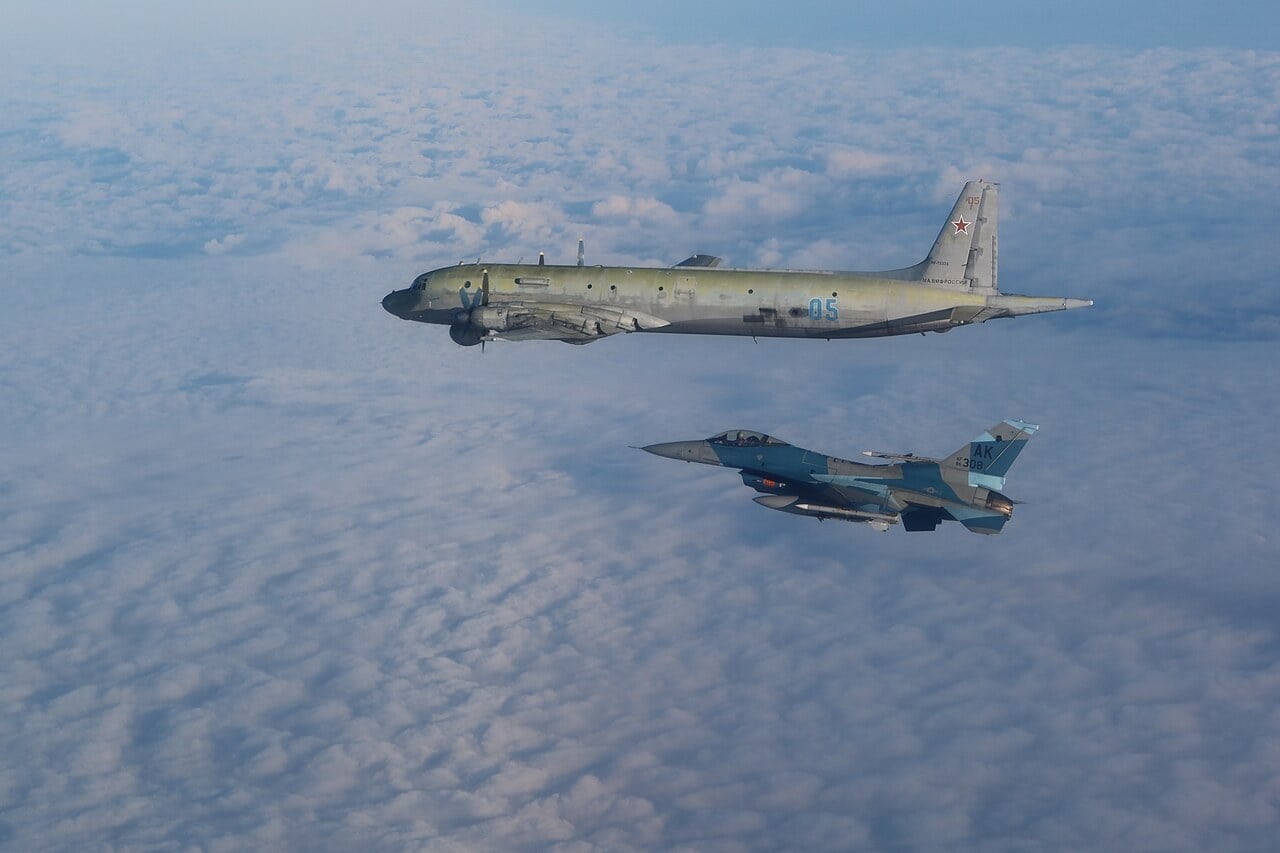 A NORAD F-16 Fighting Falcon flying alongside a Russian Il-38 maritime patrol aircraft over clouds in the Alaska Air Defense Identification Zone