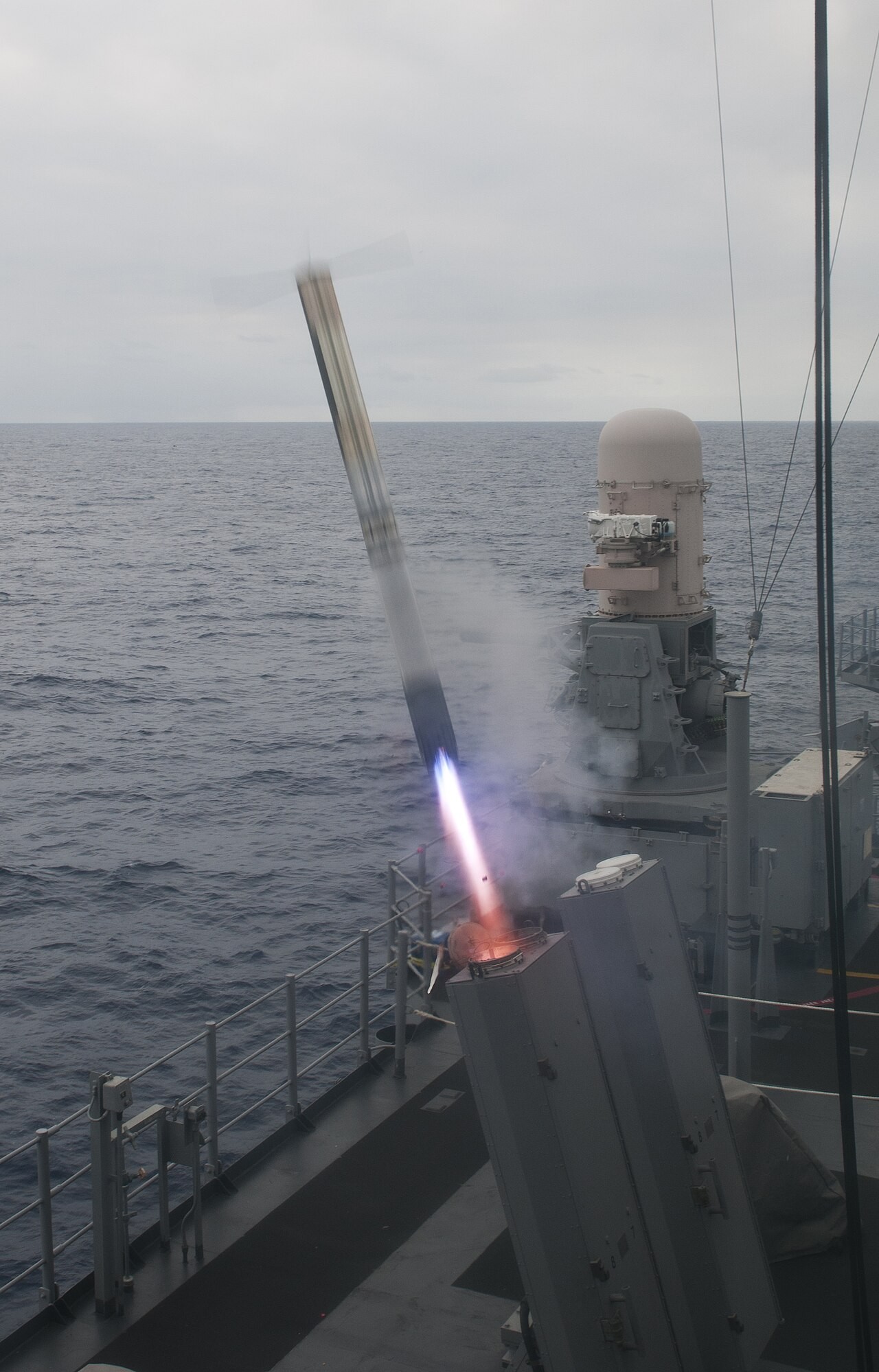 A Nulka active decoy blasts out of its launcher on the cruiser USS Chosin, with a Phalanx mount behind it