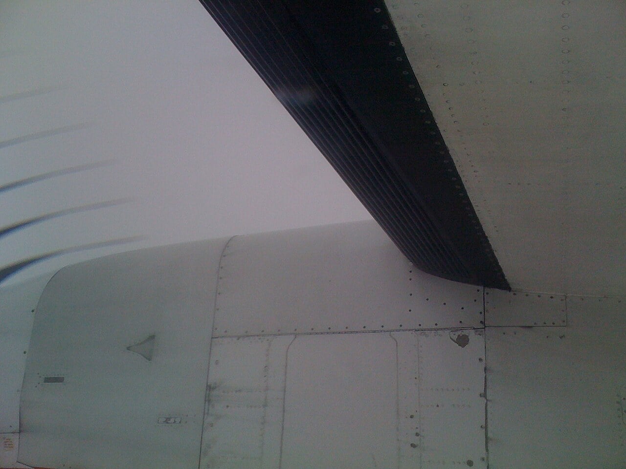The black rubber pneumatic de-icing boot on the leading edge of a Bombardier Dash 8 Q400 wing, seen from the cabin window in flight