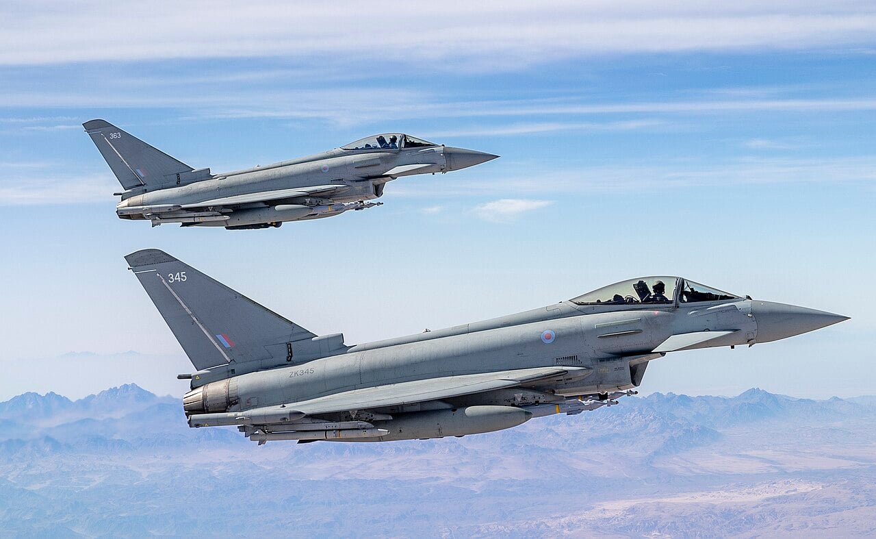 Two RAF Typhoon FGR4 fighters flying in formation over desert mountains