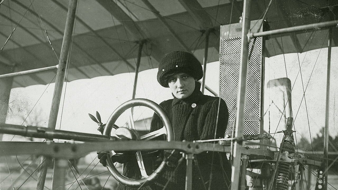 Raymonde de Laroche in a knitted hat and sweater at the wheel of a Voisin biplane in late 1909