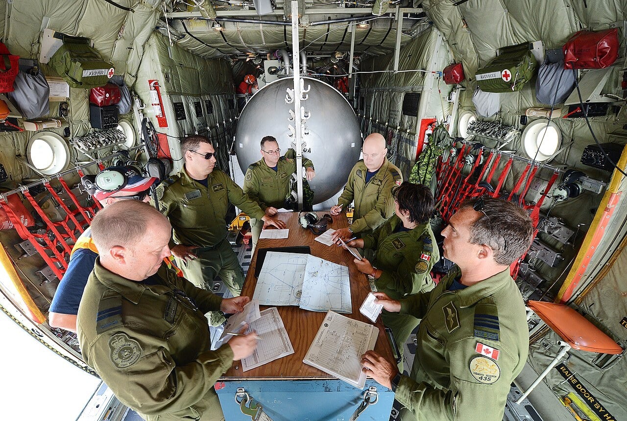 RCAF 435 Transport and Rescue Squadron crew reviewing a flight plan in the cargo hold of their Hercules tanker during RIMPAC 2014