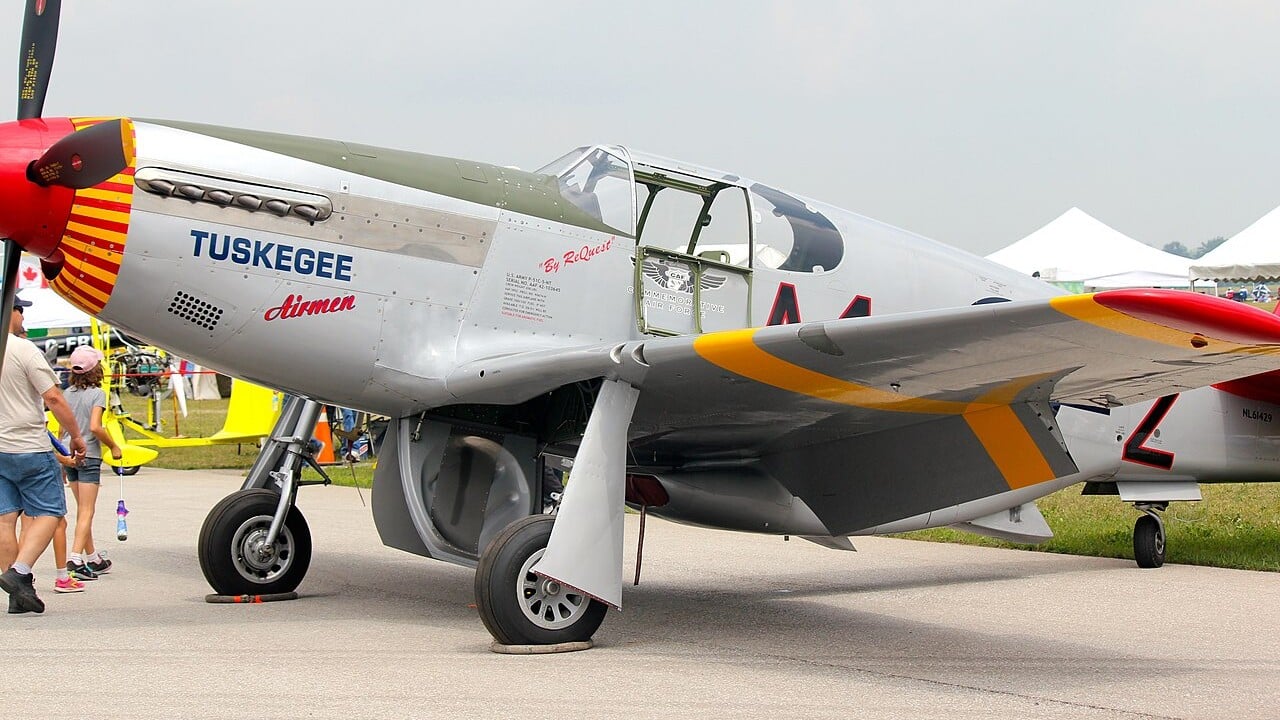 A restored P-51C Mustang painted in 332nd Fighter Group red-tail markings with Tuskegee Airmen on the nose, operated by the Commemorative Air Force Red Tail Squadron