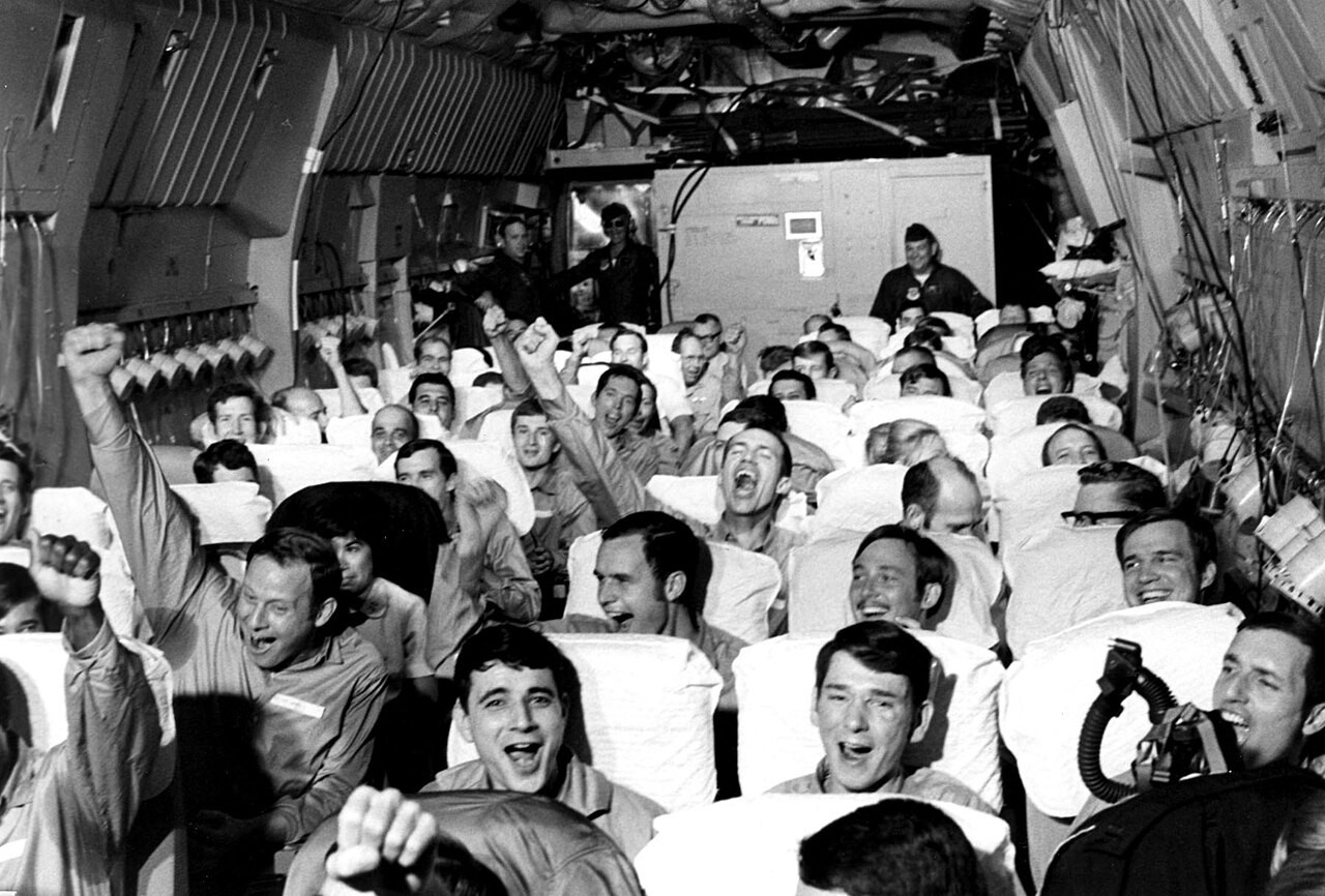 Released American prisoners of war cheering inside the cabin of a C-141A Starlifter after take-off from North Vietnam, February 1973