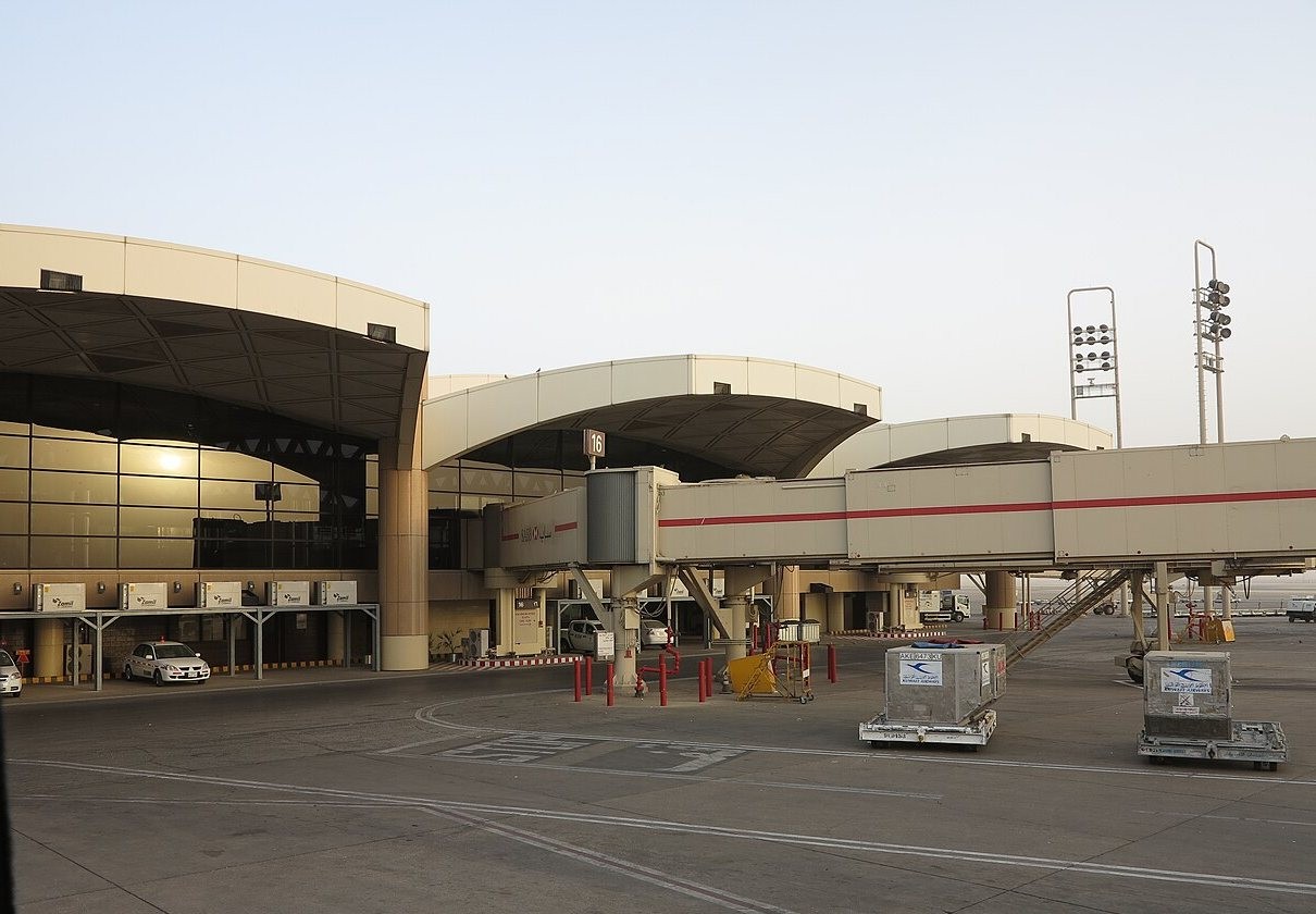 Terminal building and jet bridges at King Khalid International Airport in Riyadh with cargo containers on the apron