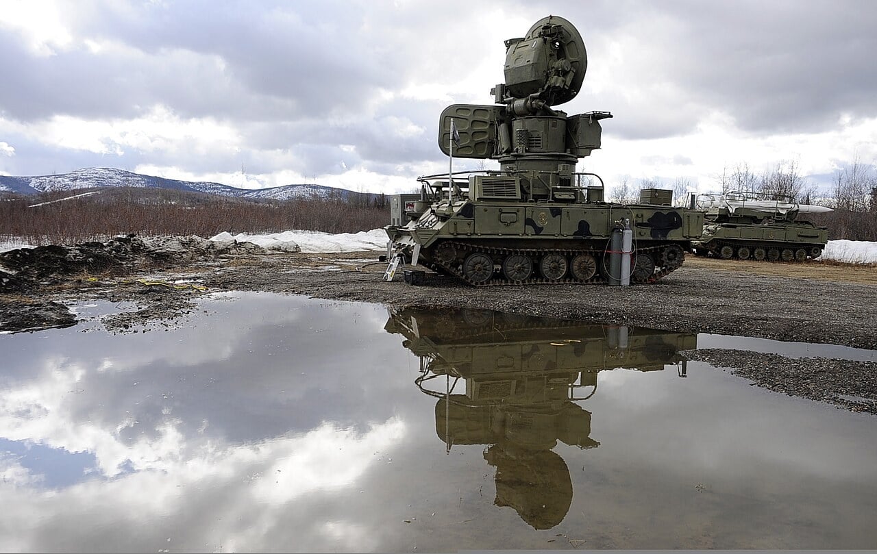 A 2K12 Kub SA-6 Straight Flush radar vehicle with a missile launcher behind it, reflected in a puddle in Alaska