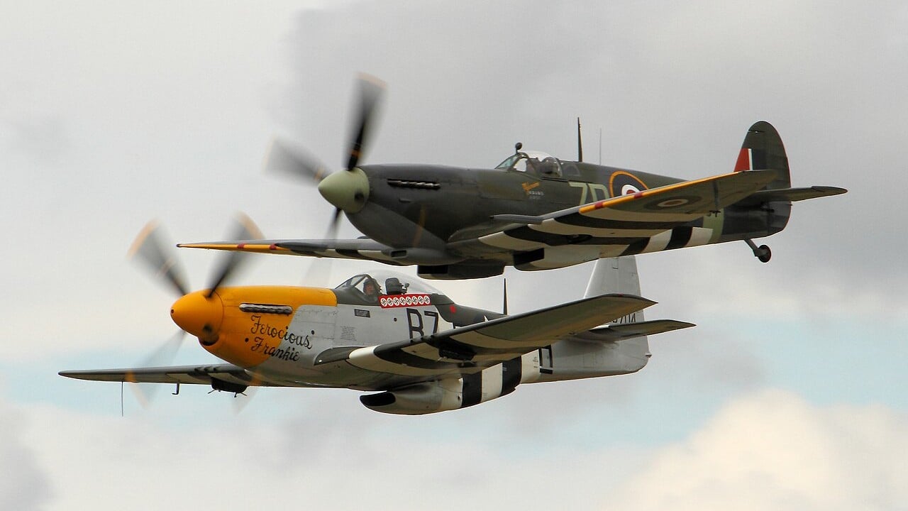 A Spitfire and a P-51 Mustang flying in formation at Dunsfold Wings and Wheels 2014 A Spitfire and a P-51 Mustang flying in formation at Dunsfold Wings and Wheels 2014