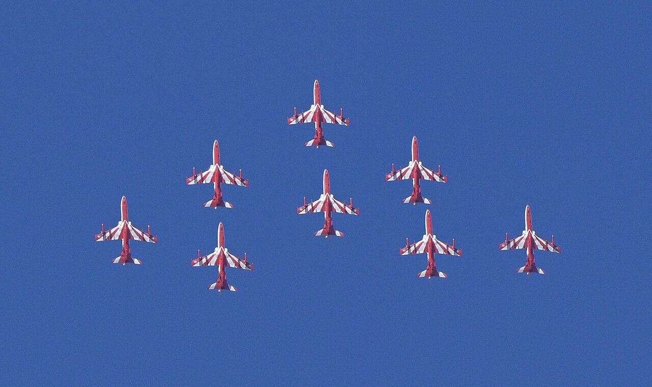 Surya Kiran Aerobatic Team nine Hawk Mk132 formation, Aero India 2025 Nine red-and-white Hawk Mk132 jets of the Indian Air Force Surya Kiran Aerobatic Team in formation against a blue sky