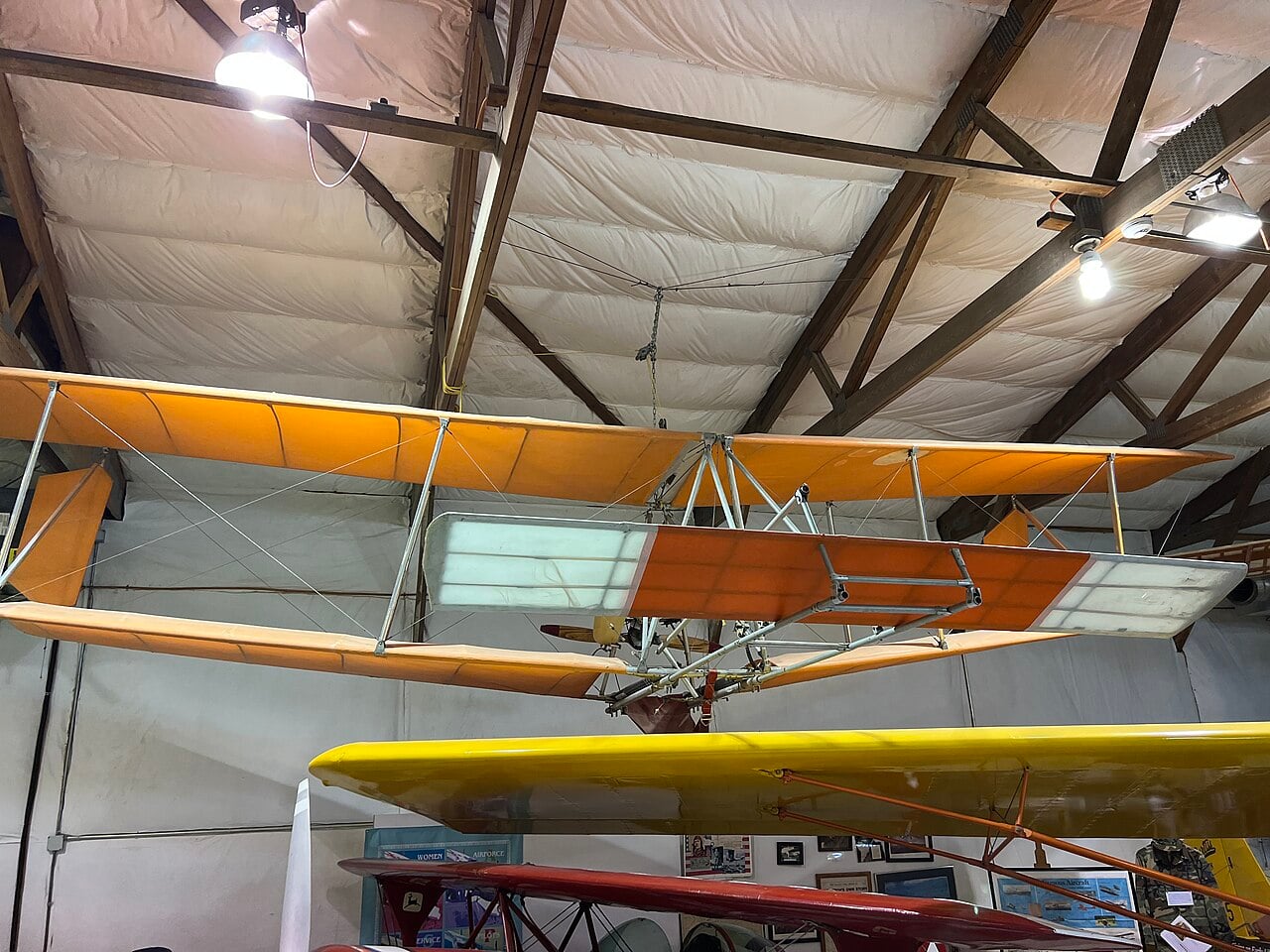 Orange UFM Easy Riser biplane ultralight hanging from the ceiling at the Iowa Aviation Museum