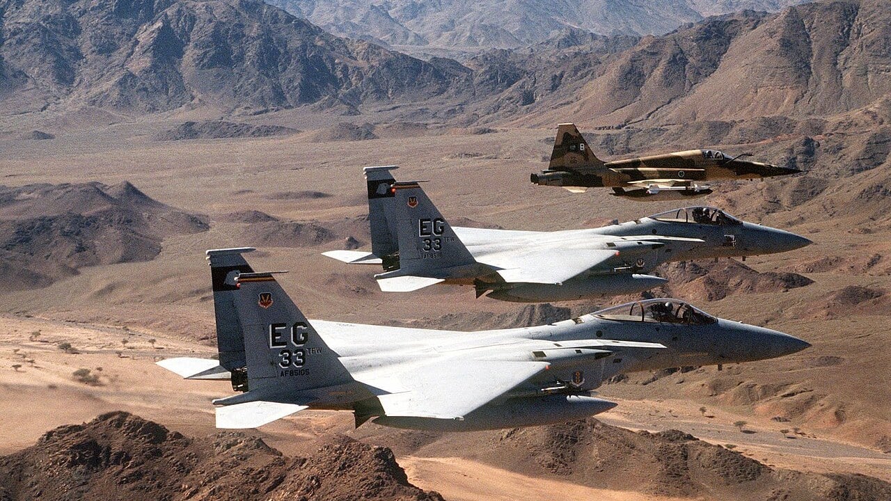 Two US Air Force F-15C Eagles of the 33rd Tactical Fighter Wing flying with a Royal Saudi Air Force F-5E over desert mountains during Operation Desert Storm